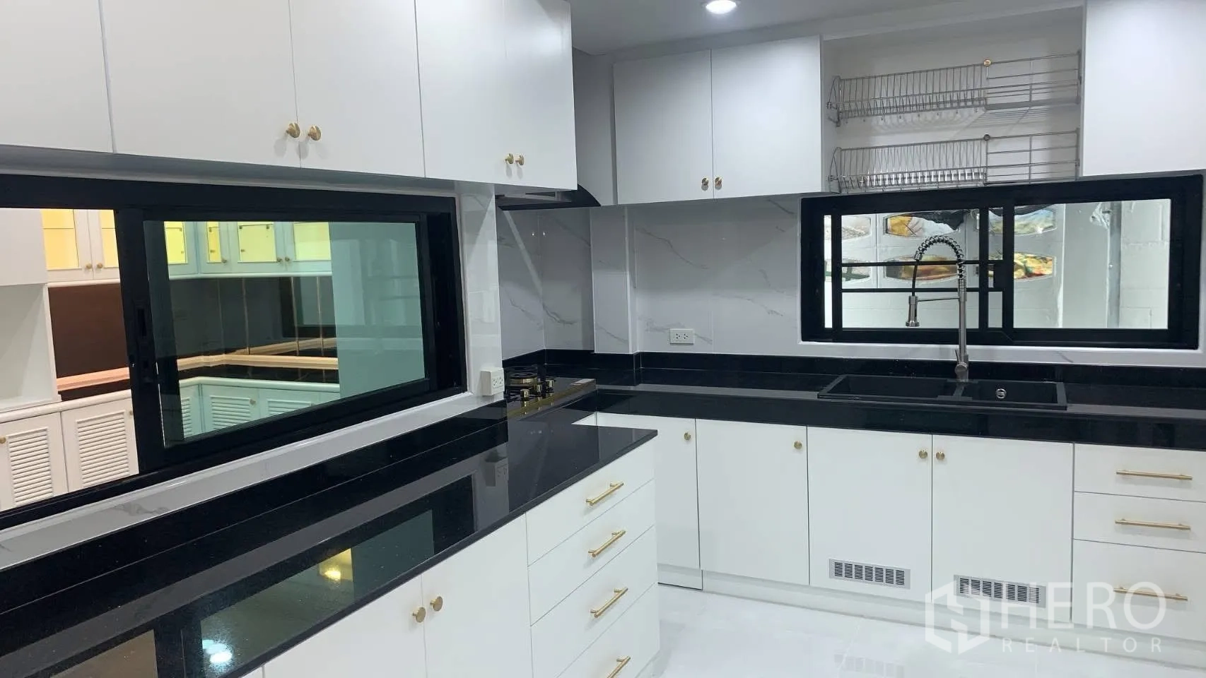 独栋房屋 for rent in Lat Phrao, Bangkok - 明亮厨房，白色橱柜、黑色台面与水槽。