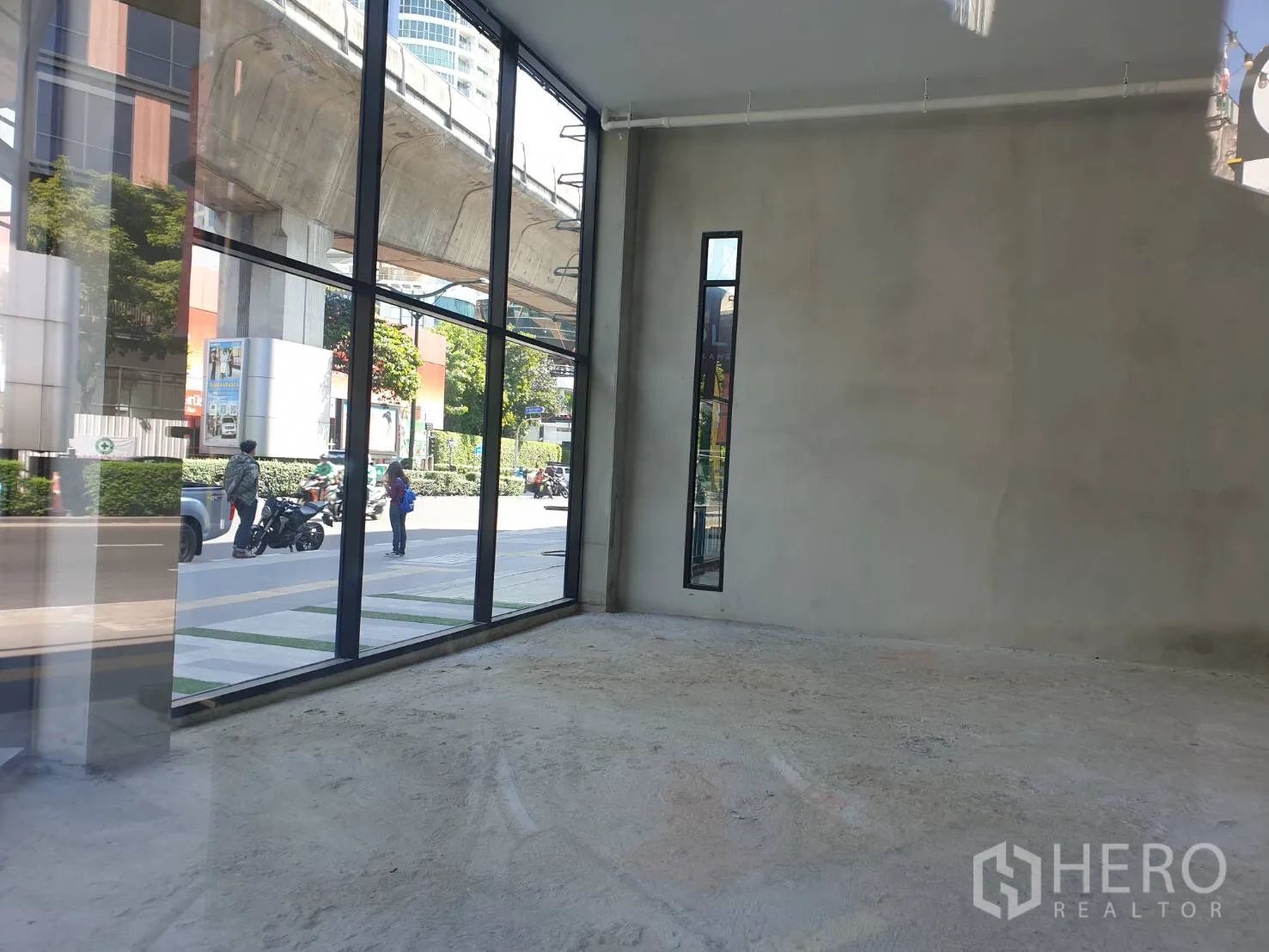 零售空间 出租在Watthana, Bangkok - 店内视角，落地窗朝向素坤逸道路与外侧高架BTS轨道。