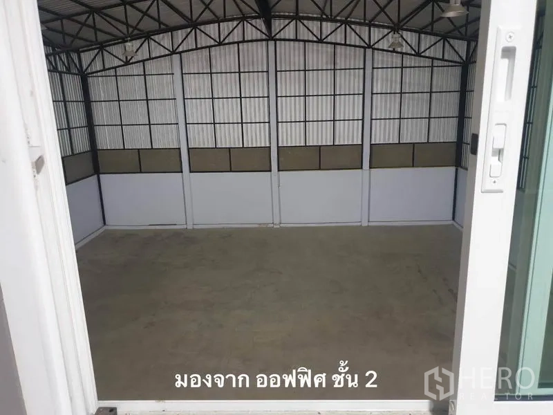 Warehouse for rent in Bang Kapi, Bangkok - Empty storage hall viewed from the second-floor office, showing a steel truss roof and high walls.