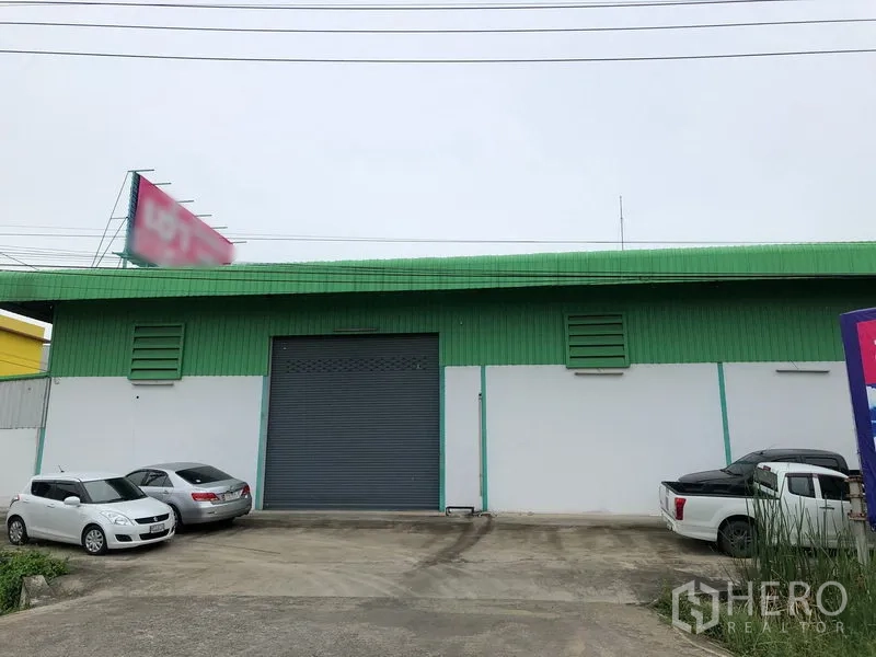 工厂 出租在Pathum Thani - 仓库正面，绿色金属墙面，大型卷闸门及停车位。