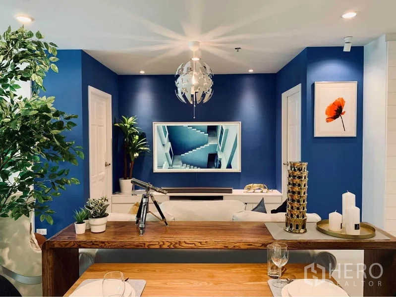 คอนโด ให้เช่าในWatthana, Bangkok - มุมโต๊ะอาหารมองไปยังผนังทีวีสีน้ำเงินและโคมไฟเพดานดีไซน์