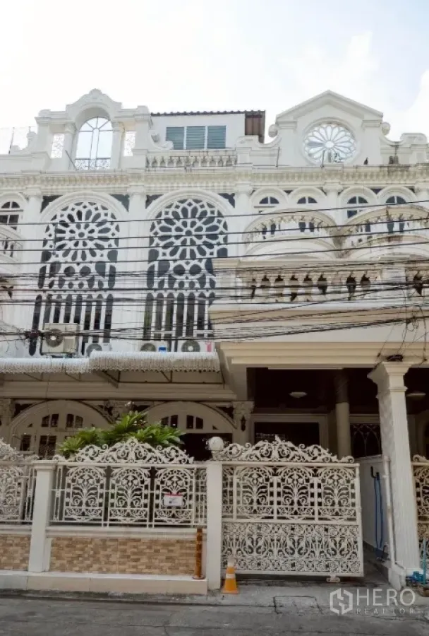 Townhouse for rent in Khlong Toei, Bangkok - Ornate white townhouse facade with arched windows and a decorative wrought-iron gate.