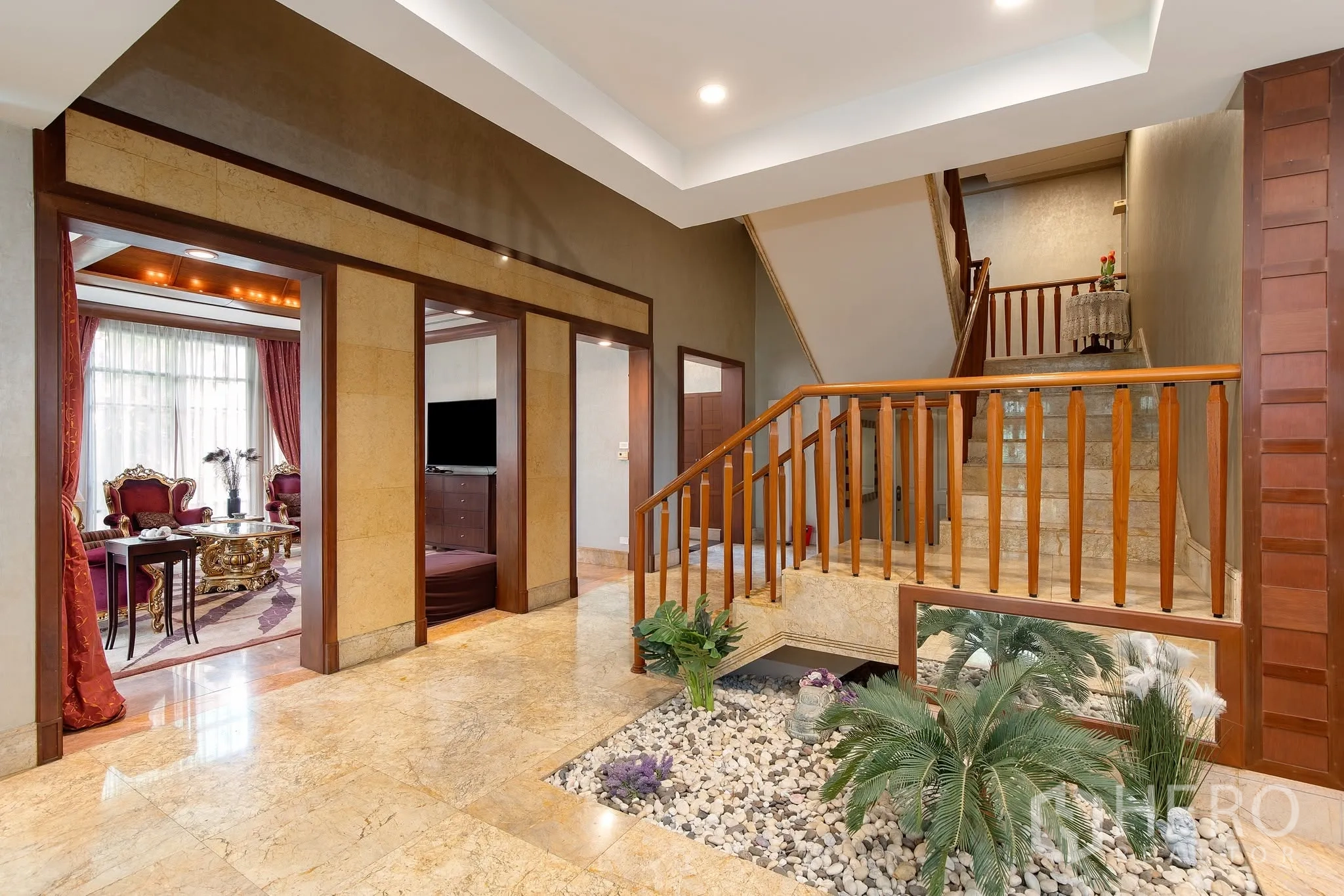独栋房屋 for rent or sale in Watthana, Bangkok - 开放空间含中岛厨房、玻璃陈列柜与楼梯。
