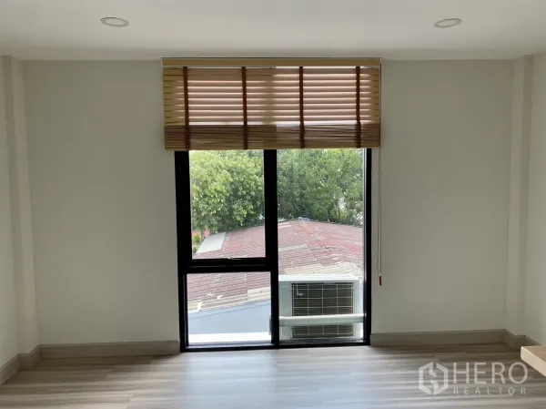 Home Office for rent or sale in Phra Khanong, Bangkok - Room with tall window and external air-conditioning unit view, wood flooring.