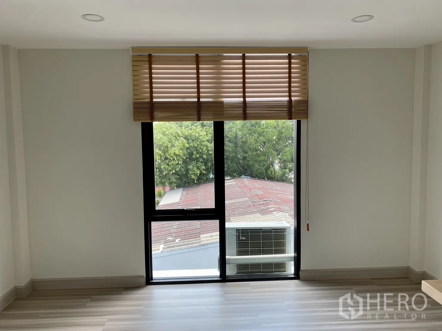 Home Office for rent or sale in Phra Khanong, Bangkok - Room with tall window and external air-conditioning unit view, wood flooring.