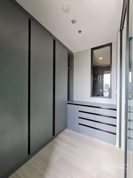 公寓 出售 - 步入式衣帽间走廊，设高柜、抽屉与镜面，旁有窗户采光。