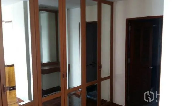 Condominium for rent in Watthana, Bangkok - Hallway with mirrored built-in wooden wardrobes and interior doors.