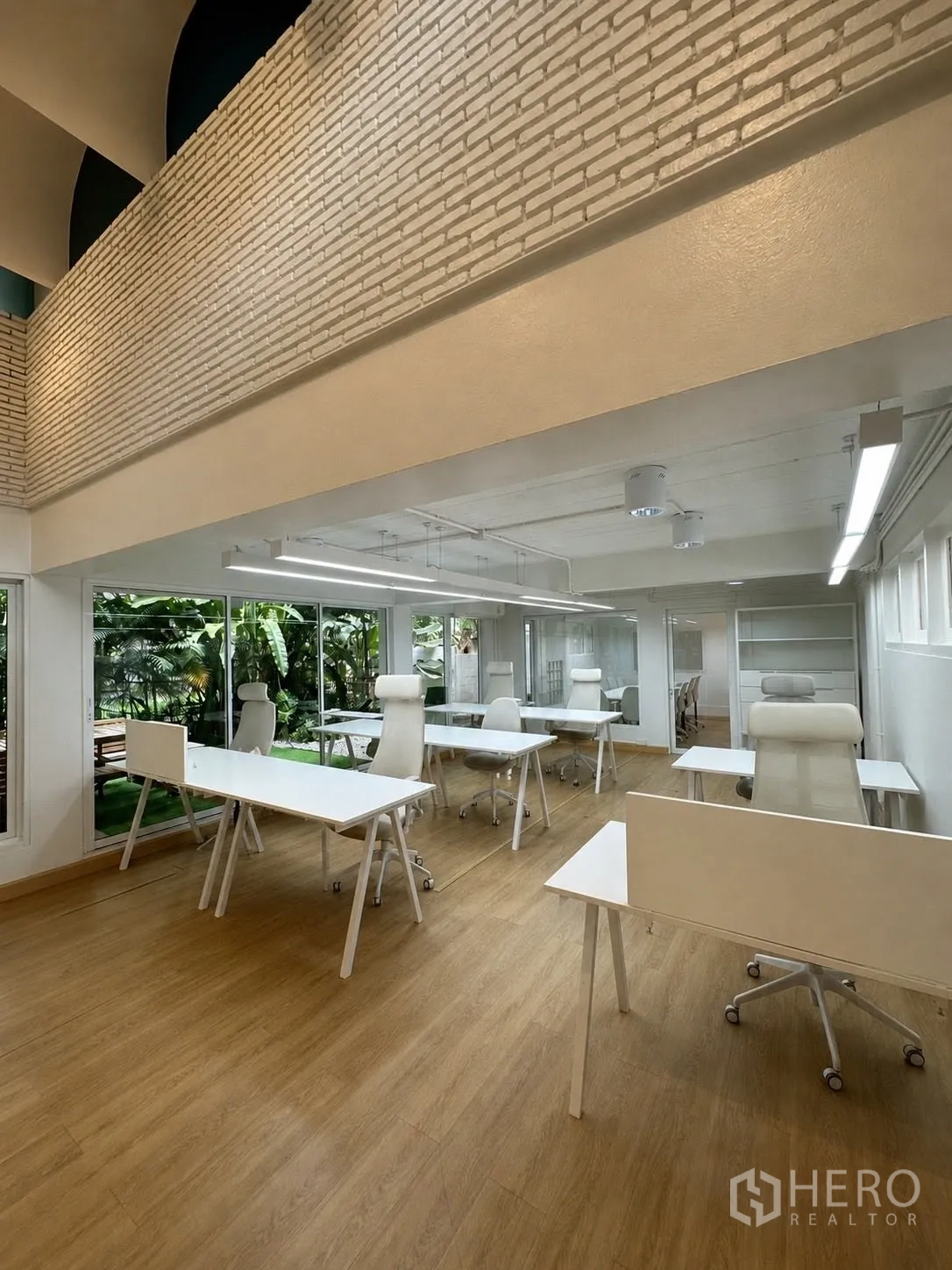 Office Space for rent in Phaya Thai, Bangkok - Open-plan office with high ceiling, brick feature wall and desks.