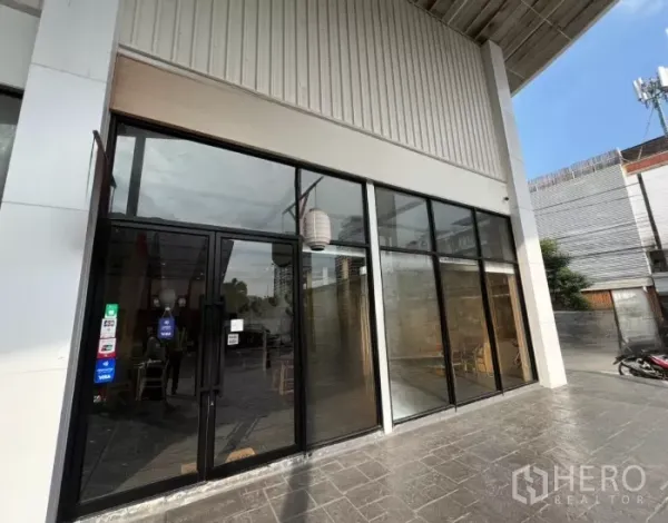 พื้นที่ขายปลีก ให้เช่าในWatthana, Bangkok - ประตูทางเข้ากระจกกรอบดำ และผนังกระจกสูงติดทางเดินหิน.