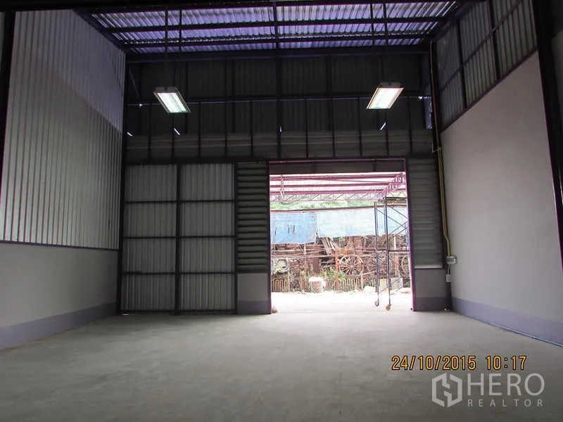 货栈 出租在Bang Khen, Bangkok - 大型金属卷闸门与明亮的装卸区，通向院子。