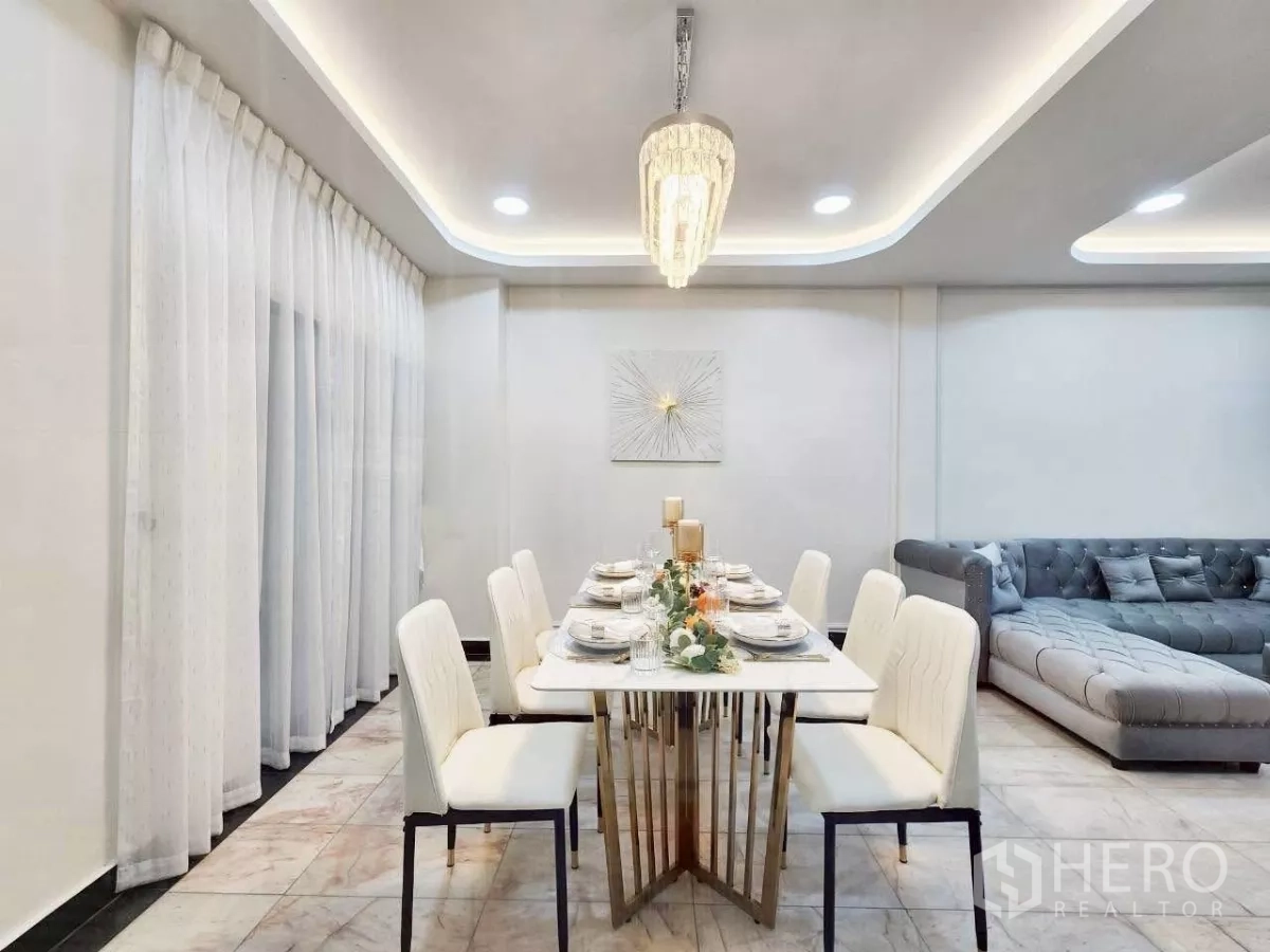 ทาวน์เฮาส์ ให้เช่าในHuai Khwang, Bangkok - โต๊ะอาหารหกที่นั่ง เก้าอี้สีขาว ใต้โคมระย้าคริสตัลข้างผ้าม่านยาว