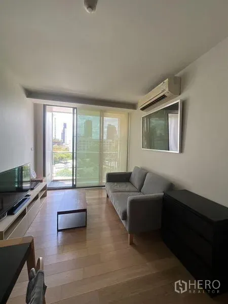 คอนโด ให้เช่าหรือขายในWatthana, Bangkok - ห้องนั่งเล่นสว่างพร้อมโซฟา ชั้นวางทีวี และประตูกระจกบานเลื่อนออกไประเบียงวิวเมือง
