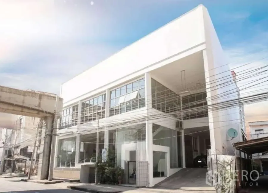 展厅 出租或出售在Bangkok Yai, Bangkok - 现代白色商业建筑，通高玻璃立面与车辆坡道。