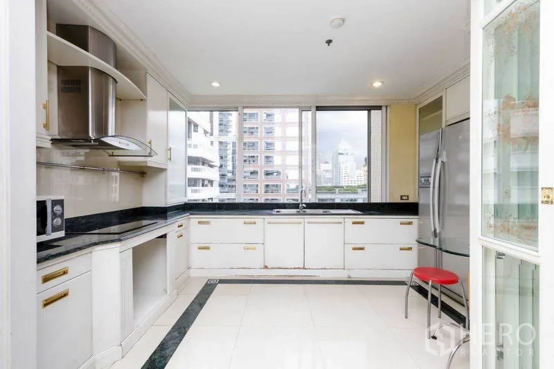 Condominium for rent or sale in Pathum Wan, Bangkok - U-shaped kitchen with large windows, stainless fridge, and ample storage.