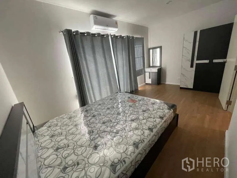 Townhouse for rent or sale in Phasi Charoen, Bangkok - Bright bedroom with air-conditioning, grey curtains, wood floors and vanity.