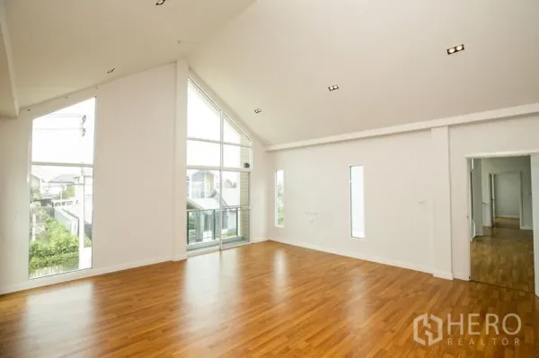 บ้าน ให้เช่าหรือขายในLam Luk Ka, Pathum Thani - ห้องนั่งเล่นเพดานสูงโปร่ง ผนังกระจกเต็มผนัง พื้นไม้