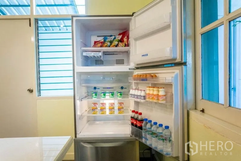 带办公室的家 出租在Suan Luang, Bangkok - 厨房内打开的冰箱，饮料与零食一应俱全。
