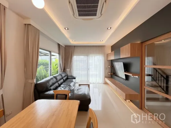 独立式住宅 出租或出售在Khlong Luang, Pathum Thani - 采光明亮的客厅，黑色皮沙发与通向花园的推拉门