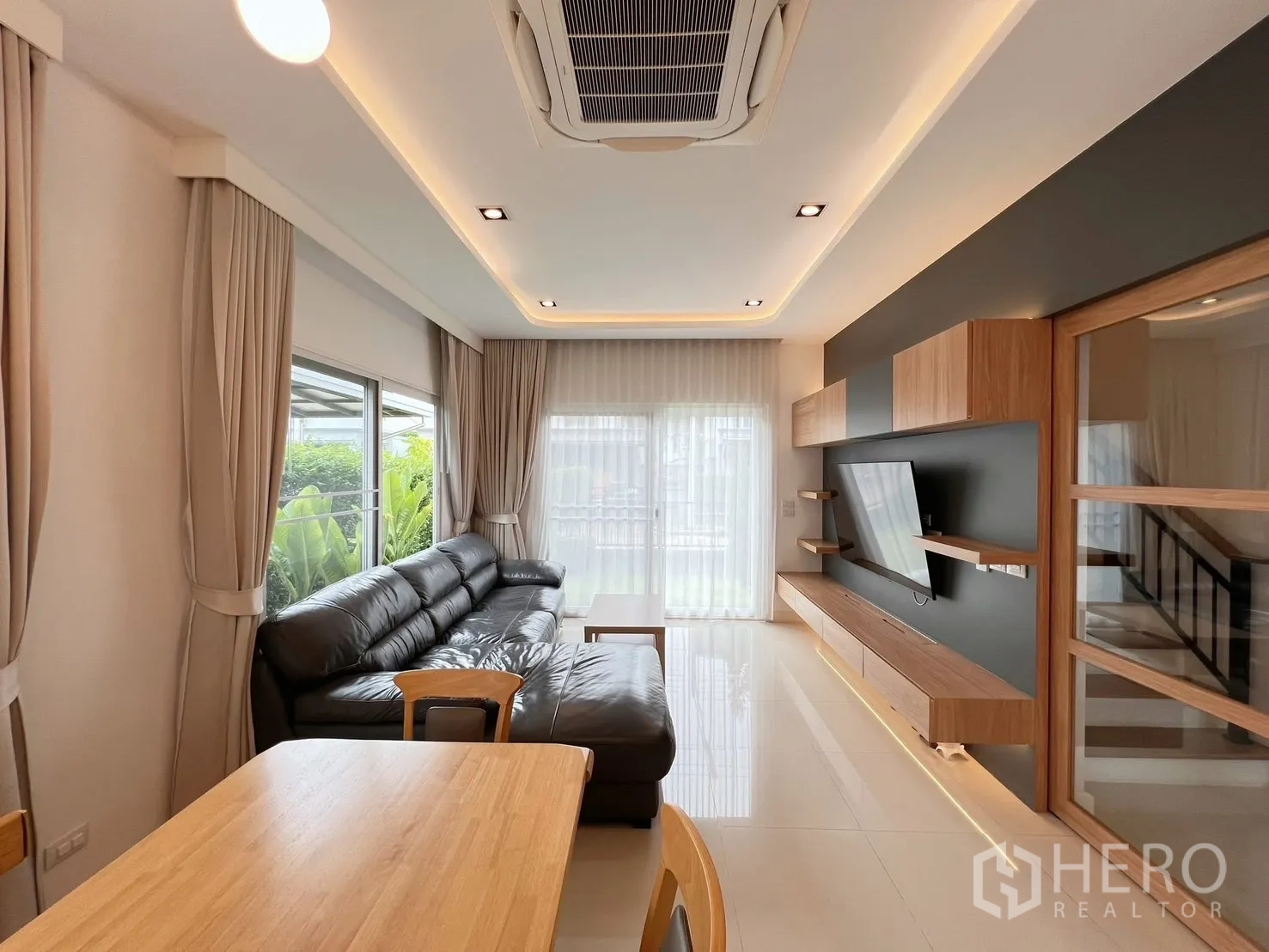 独立式住宅 出租或出售在Khlong Luang, Pathum Thani - 采光明亮的客厅，黑色皮沙发与通向花园的推拉门