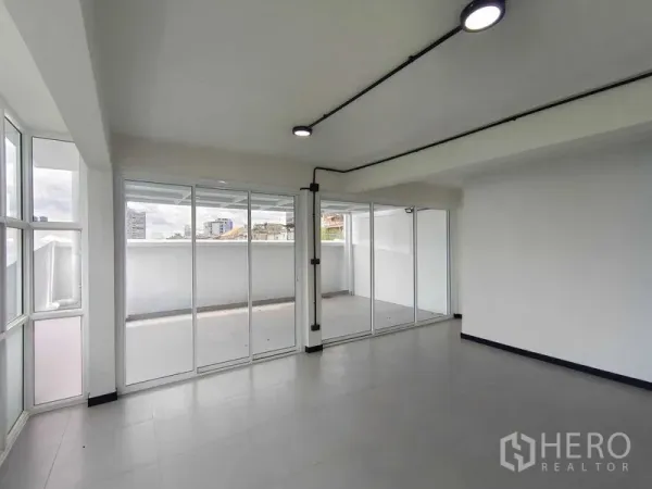 Townhouse for sale in Bang Phlat, Bangkok - Bright living area with floor-to-ceiling sliding doors opening to a large balcony and city views.