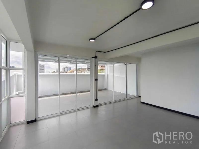 Townhouse for sale in Bang Phlat, Bangkok - Bright living area with floor-to-ceiling sliding doors opening to a large balcony and city views.