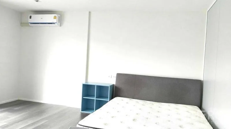 Home Office for rent - Minimal bedroom with upholstered bed, air conditioner and side shelving.