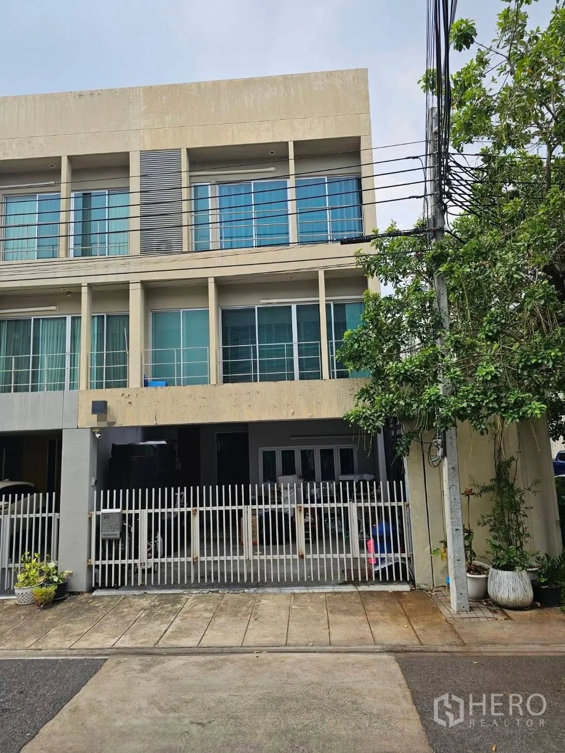 联排别墅 for sale in Suan Luang, Bangkok - 三层联排别墅外立面，大片玻璃、阳台和大门围栏。