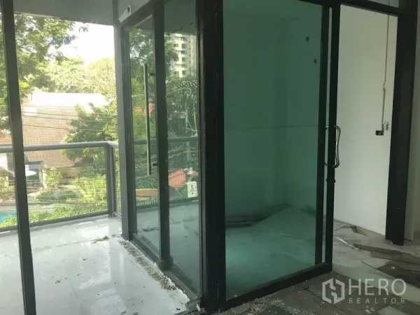 零售空间 出租在Watthana, Bangkok - 小型玻璃隔间，连接阳台，可见树梢景观。
