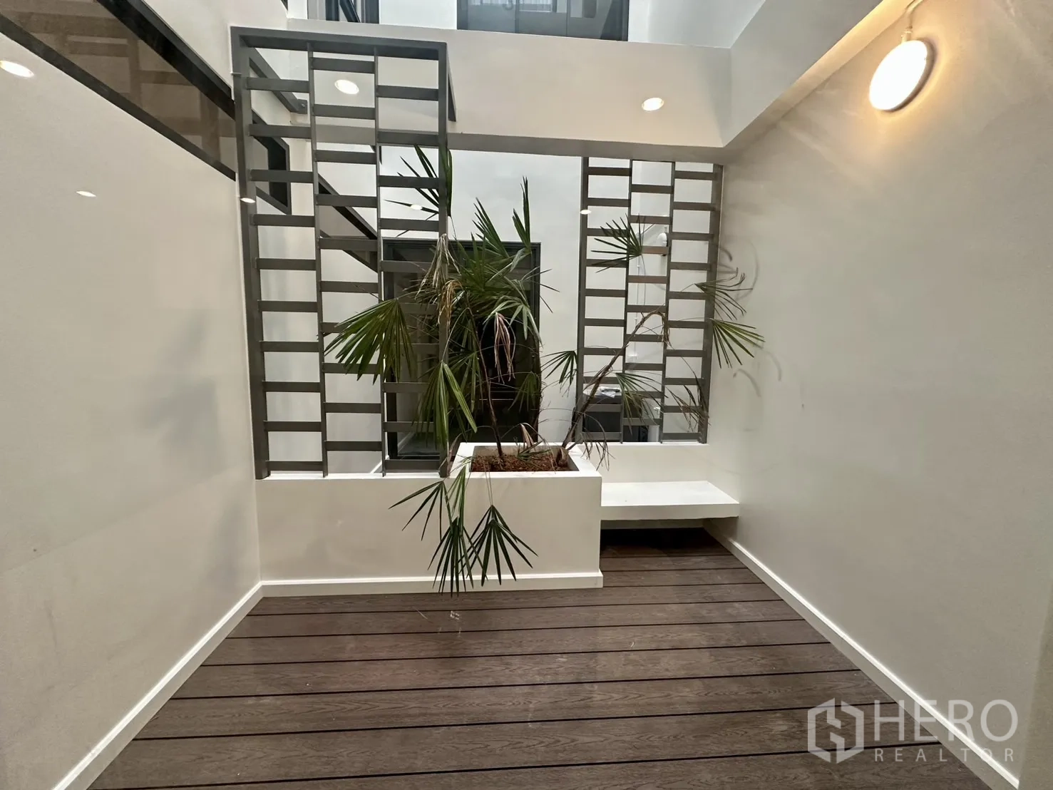 带办公室的家 出租在Phra Khanong, Bangkok - 室内中庭，木质平台、种植池与装饰金属格栅。