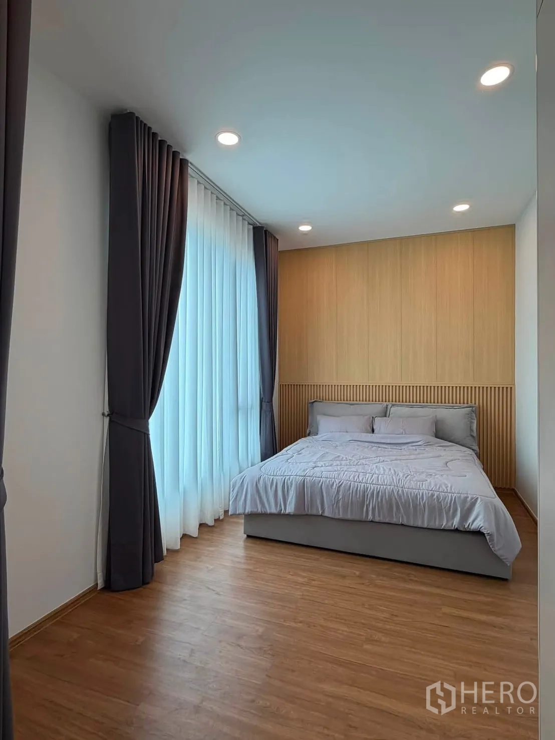 Townhouse for rent in Bang Phli, Samut Prakan - Master bedroom with floor-to-ceiling windows, blackout curtains and wood flooring.