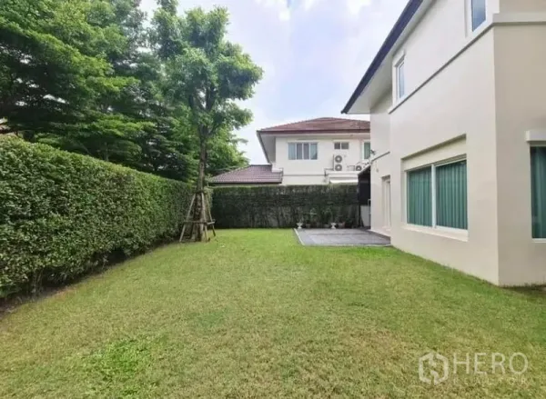 บ้าน ให้เช่าหรือขายในLat Krabang, Bangkok - สนามหญ้ากว้างข้างตัวบ้าน พร้อมพุ่มไม้แนวริมรั้ว ต้นไม้และระเบียงเล็ก