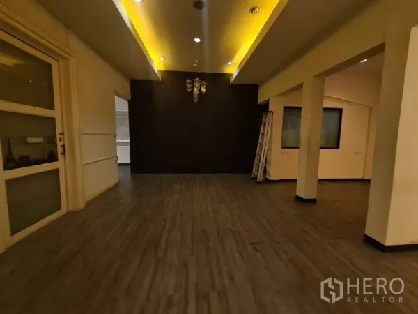 零售空间 出租在Watthana, Bangkok - 画廊风空间，天花灯槽与吊灯，深色背景墙。