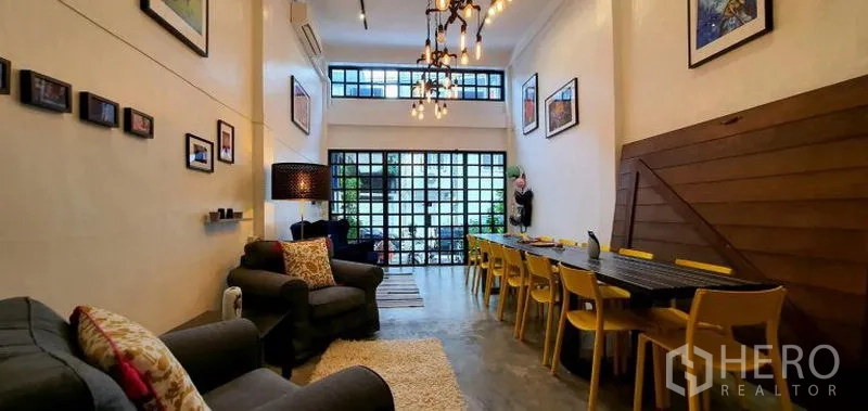 ทาวน์เฮาส์ ให้เช่าในKhlong Toei, Bangkok - มุมกว้างของห้องนั่งเล่นเพดานสูง โคมไฟสไตล์อินดัสเทรียล ผนังแกลเลอรี และพื้นปูนขัดมัน