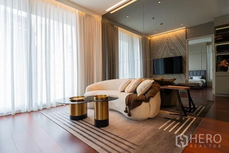 公寓 出租在Watthana, Bangkok - 客厅设弧形沙发、金色茶几、大地毯与落地窗帘。