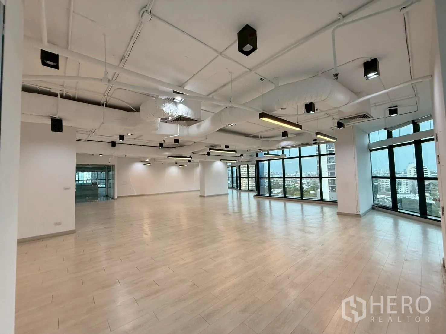 Office Space for rent in Watthana, Bangkok - Spacious open-plan office with exposed ducts, pendant lights, and panoramic windows.