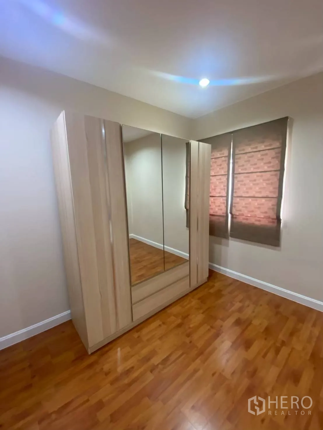 Townhouse for rent in Bang Kapi, Bangkok - Bedroom corner with mirrored wardrobe and window blinds.