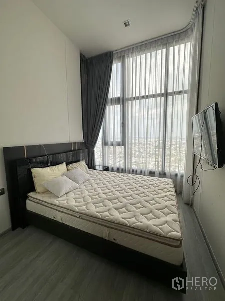 คอนโด ให้เช่าในPhra Khanong, Bangkok - ห้องนอนหลักเตียงขนาดใหญ่ ทีวีติดผนัง และมุมหน้าต่างผ้าม่านสูงวิวเมือง