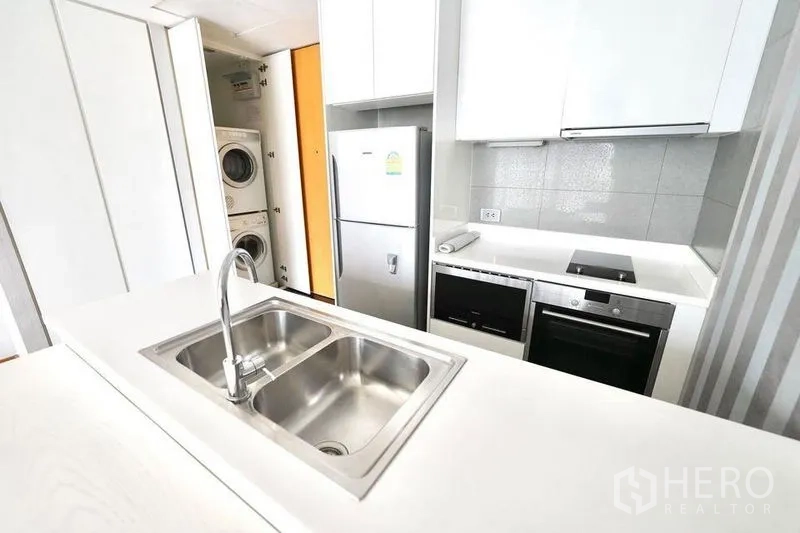 公寓 出租或出售在Watthana, Bangkok - 紧凑厨区，双槽水槽、灶台、烤箱、冰箱及叠放洗烘一体机。