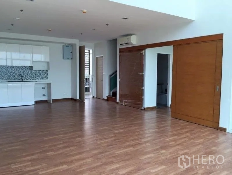 公寓 出售在Bang Na, Bangkok - 开放式起居餐厅区，白色简洁厨房、木地板与木质推拉门。