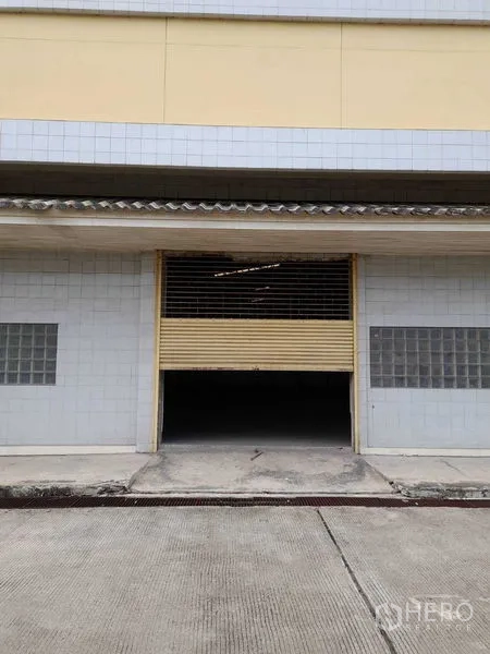 คลังสินค้า ให้เช่าในYan Nawa, Bangkok - ด้านหน้าโกดังพร้อมประตูม้วนเปิดบางส่วน ผนังกระเบื้องและทางลาดขนถ่าย