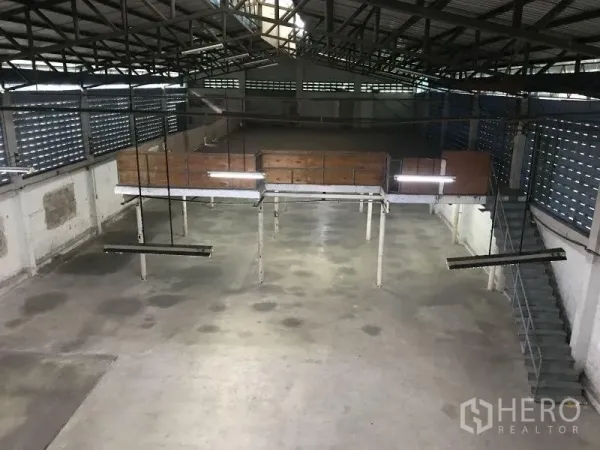 Factory for rent or sale in Krathum Baen, Samut Sakhon - Spacious warehouse interior with high steel truss roof, mezzanine platform and bright strip lighting.