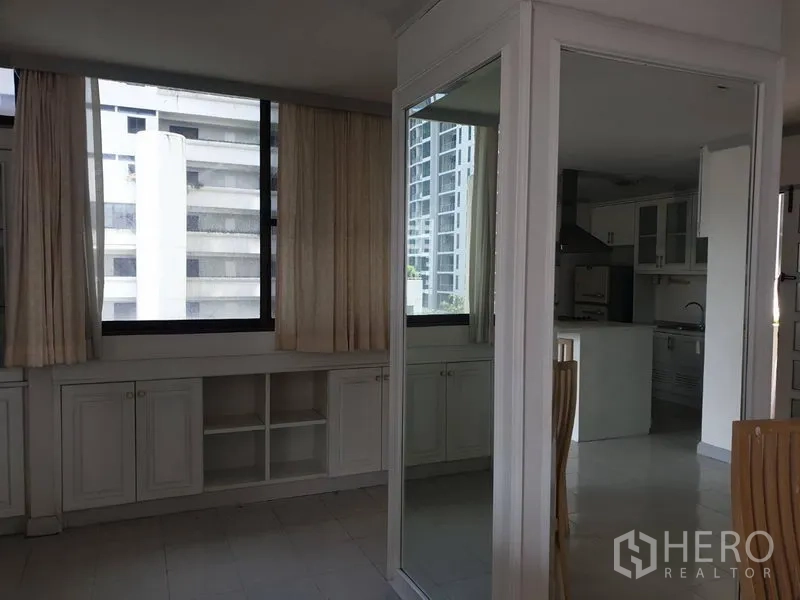 Condominium for rent in Watthana, Bangkok - Corner room with large windows, mirrored wall, and storage cabinetry.