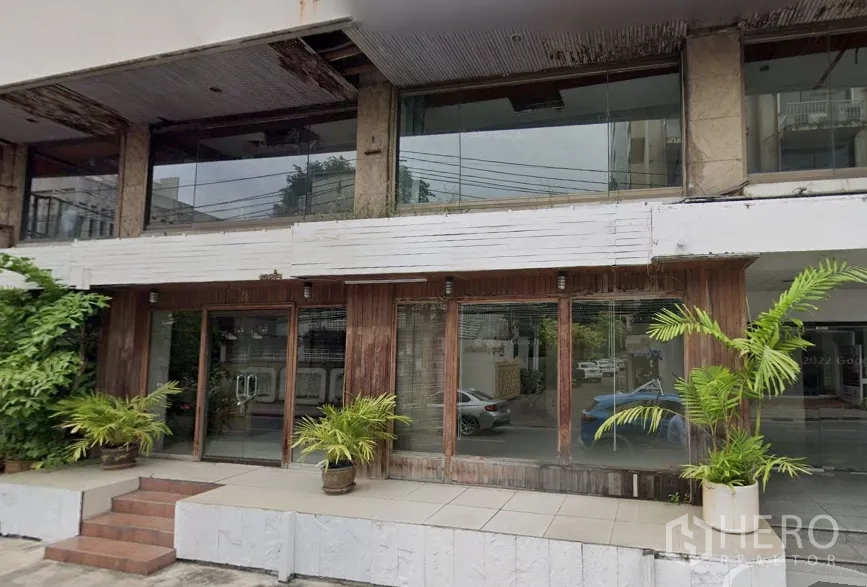 零售空间 出租在Watthana, Bangkok - 一层商铺外立面，落地玻璃橱窗、双开门、铺装台阶与盆栽，临近BTS澎蓬站。