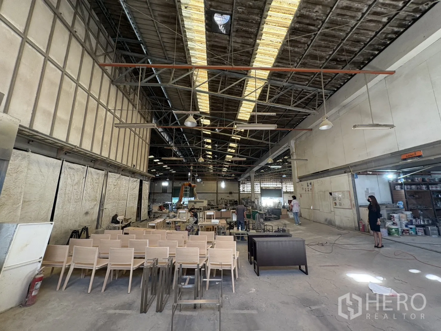 Factory for sale in Khlong Toei, Bangkok - Assembly section with rows of wooden chairs and a partitioned area
