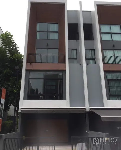 Townhouse for rent in Suan Luang, Bangkok - Modern three-storey townhouse facade with gated parking and large windows in Suan Luang, Bangkok.