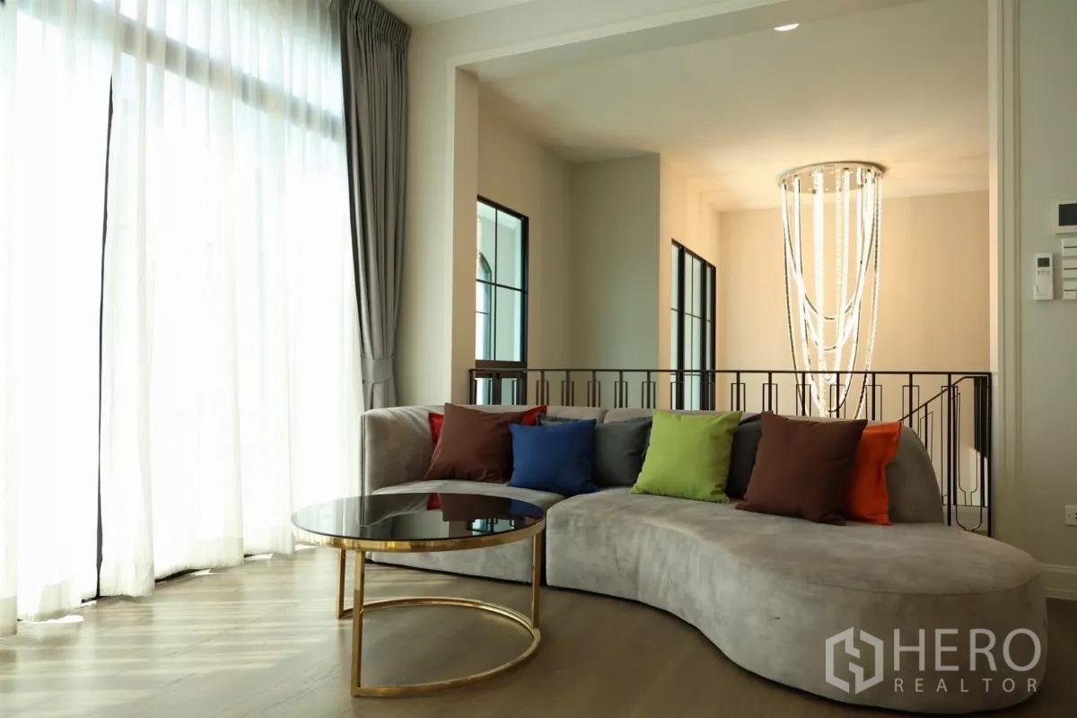 Detached House for rent or sale in Saphan Sung, Bangkok - Upper-floor living area with curved sofa, round glass coffee table, and chandelier.