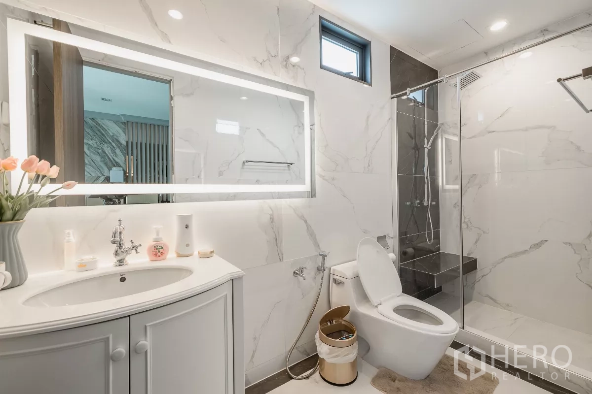 Home Office for sale in Don Mueang, Bangkok - Marble-clad bathroom with vanity, toilet and glass-enclosed shower.