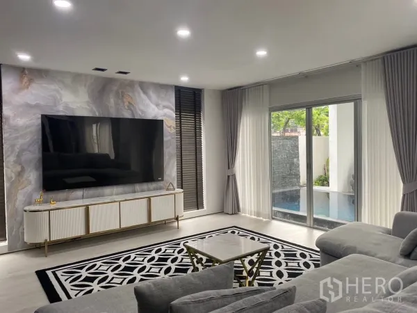 บ้าน ให้เช่าในSuan Luang, Bangkok - ห้องนั่งเล่นสว่าง ทีวีจอใหญ่ผนังลายหินอ่อน ประตูบานเลื่อนติดสระ