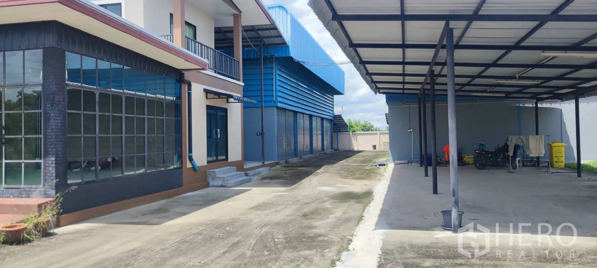 Warehouse for sale in Thung Khru, Bangkok - Service lane with office facade, warehouse shutters and large covered parking.