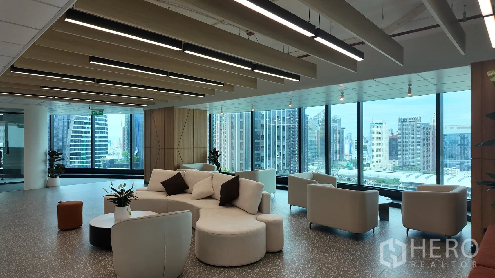 办公室 for rent in Din Daeng, Bangkok - 现代休闲区配弧形沙发与茶几，落地窗外为城市景观。